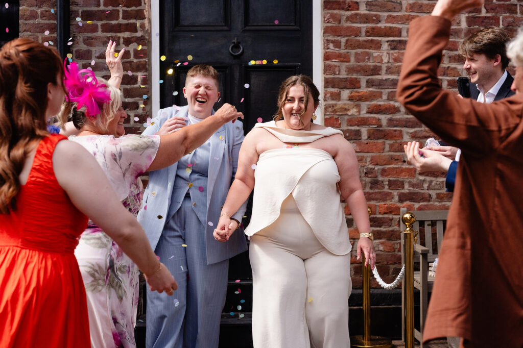 Marianne laughing as guests throw confetti over her and Emma