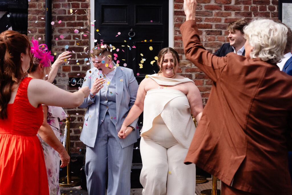 Guests throwing confetti as Marianne and Emma walk out hand in hand