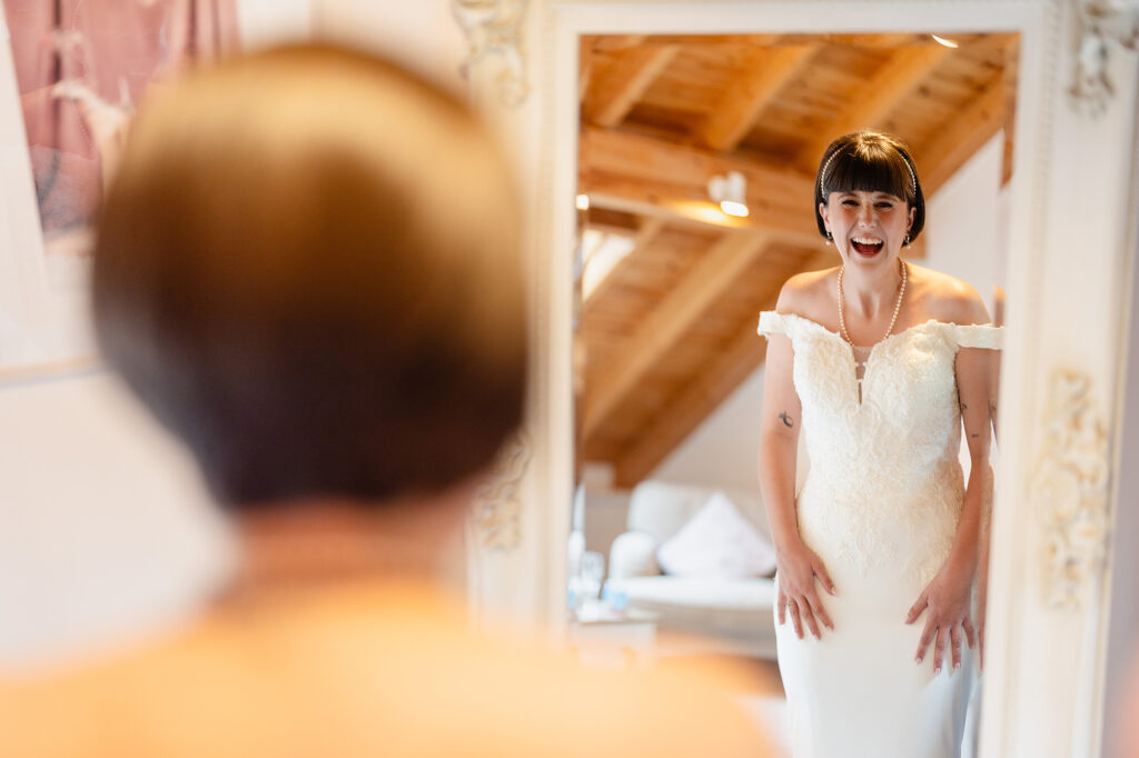 Bride laughing at her reflection in a mirror in the loft bridal room at The Oak Tree of Peover