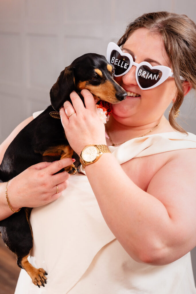 Emma in heart shaped sunglasses reading Belle and Brian, cuddling one of their sausage dogs