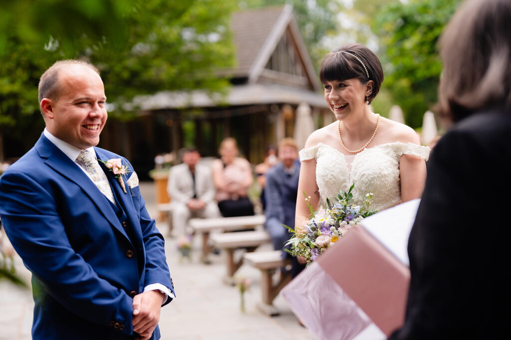 Bride and groom laughing together at the front of their outdoor ceremony