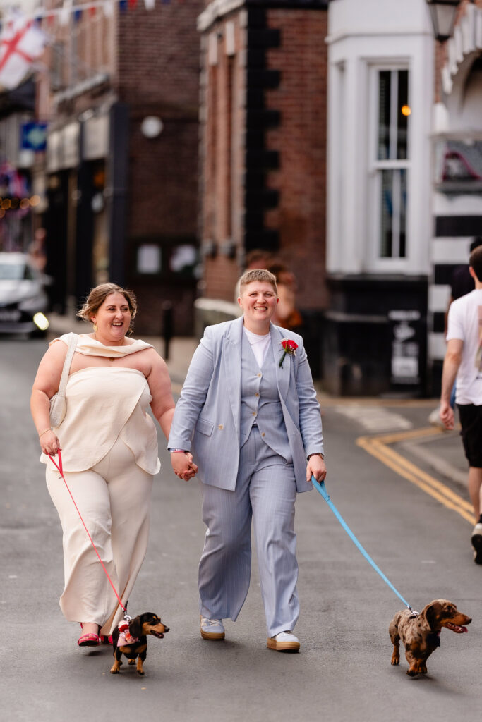 Marianne and Emma walking hand in hand down a Knutsford street with their two sausage dogs