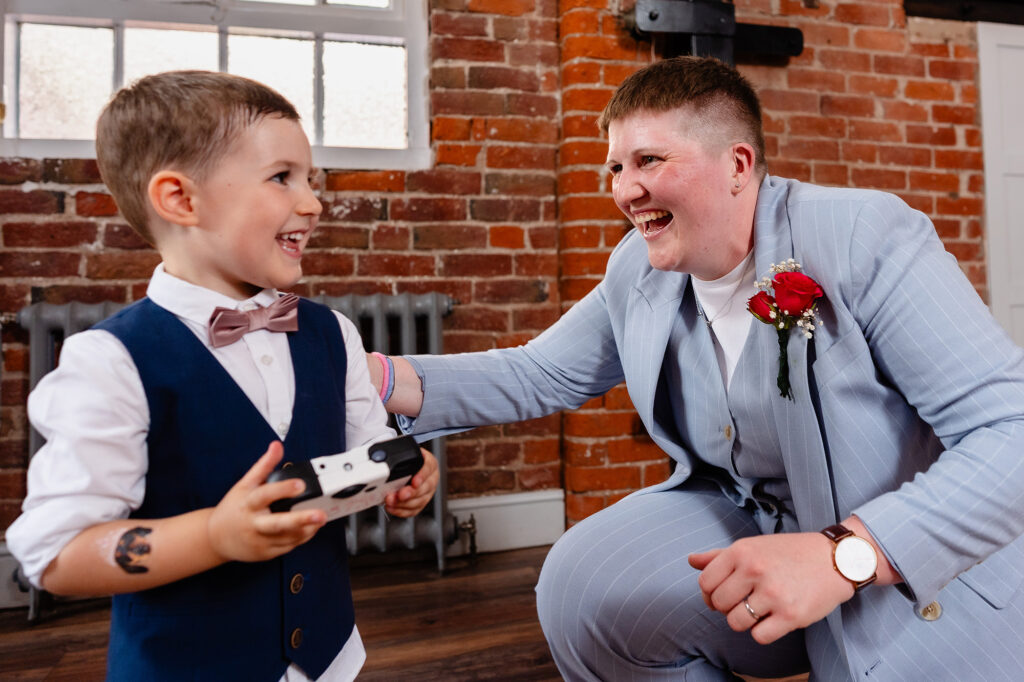 Marianne crouching and laughing with a little boy holding a camera