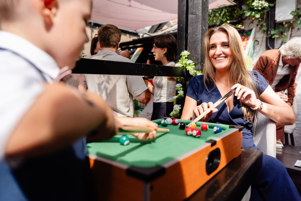 Guest smiling over a mini pool table during the afternoon of a Knutsford wedding