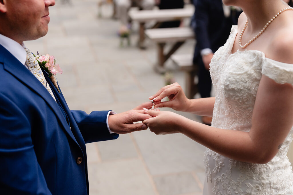 Close up of the bride sliding the wedding ring onto the groom's finger