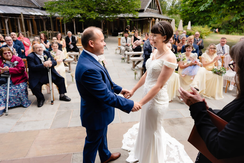 Guests clapping and laughing as the newlyweds hold hands at the end of their outdoor ceremony