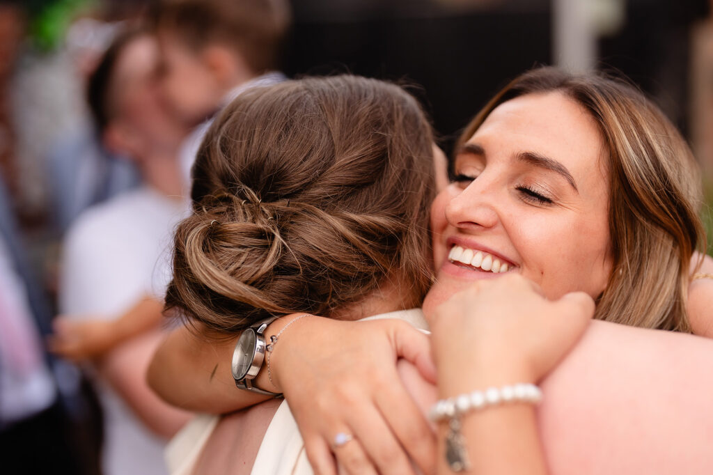 Two guests sharing a big hug, eyes closed and smiling