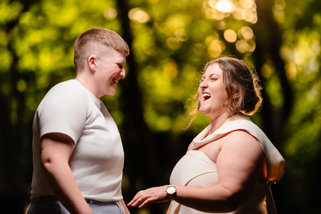 Marianne and Emma laughing together in golden evening light among the trees, Knutsford wedding photographer