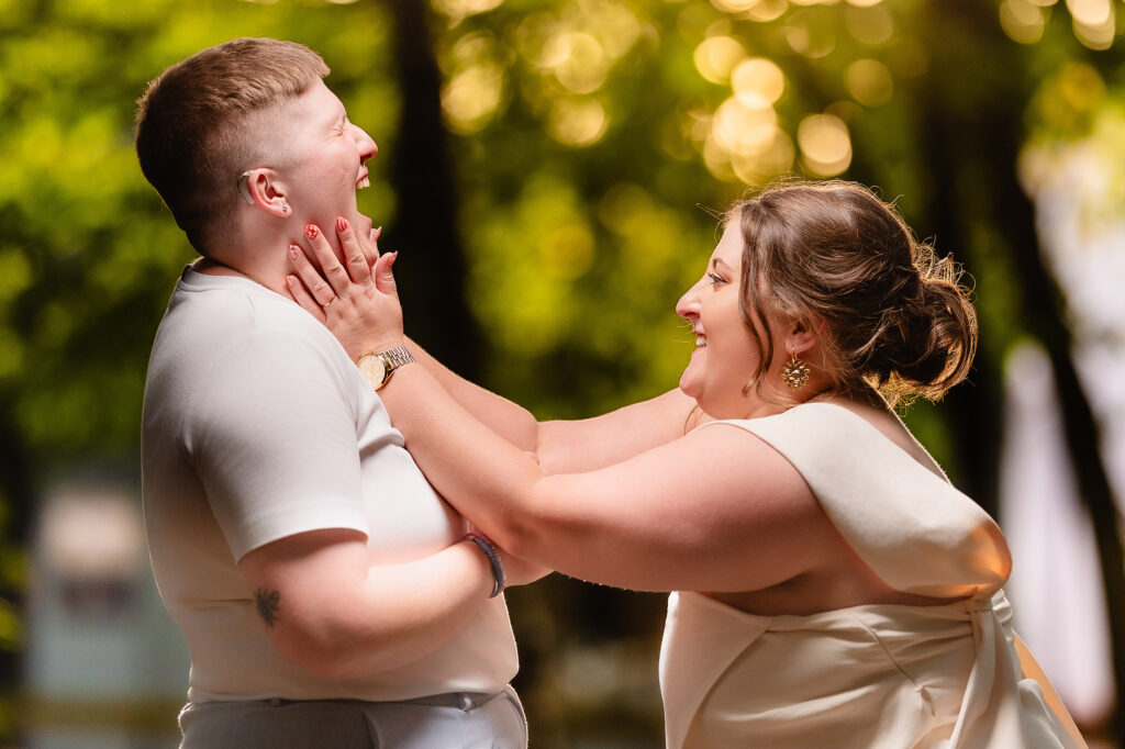 Emma holding Marianne's face as they both laugh in the evening sun