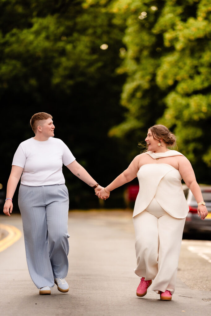Marianne and Emma walking hand in hand down a quiet Knutsford road