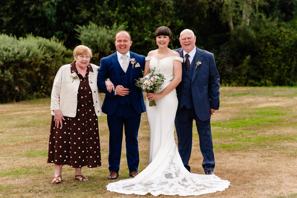 Bride and groom with a small group on the lawn at The Oak Tree of Peover