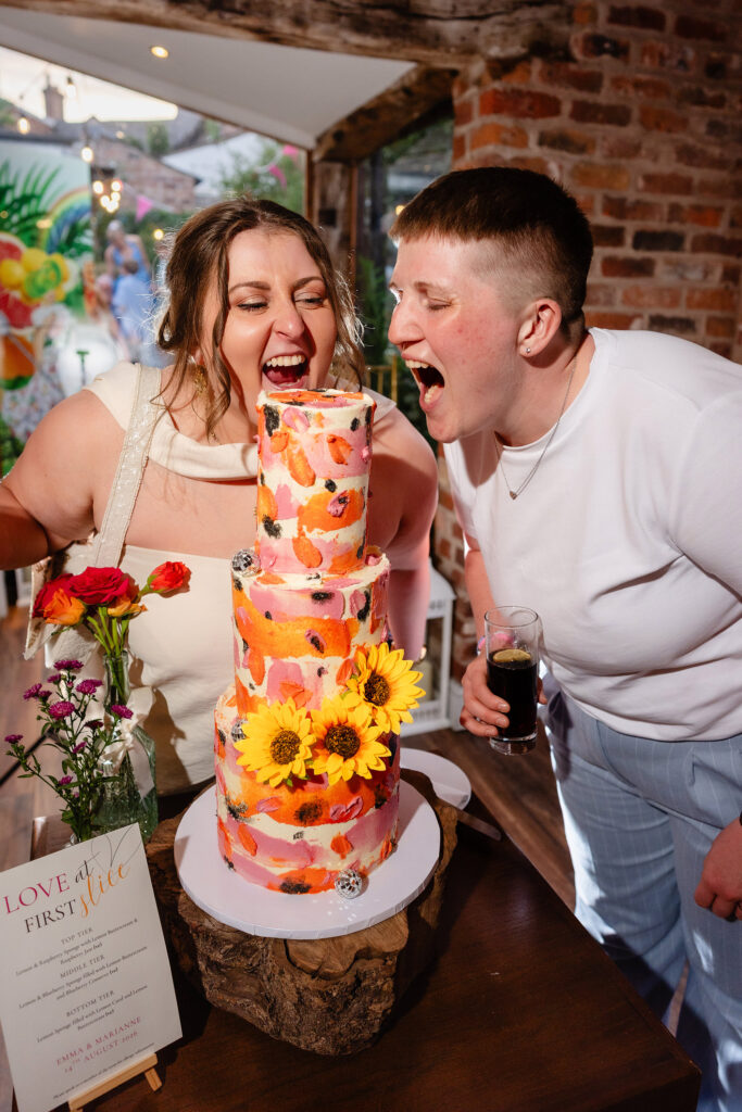 Marianne and Emma pretending to take a bite out of their sunflower wedding cake