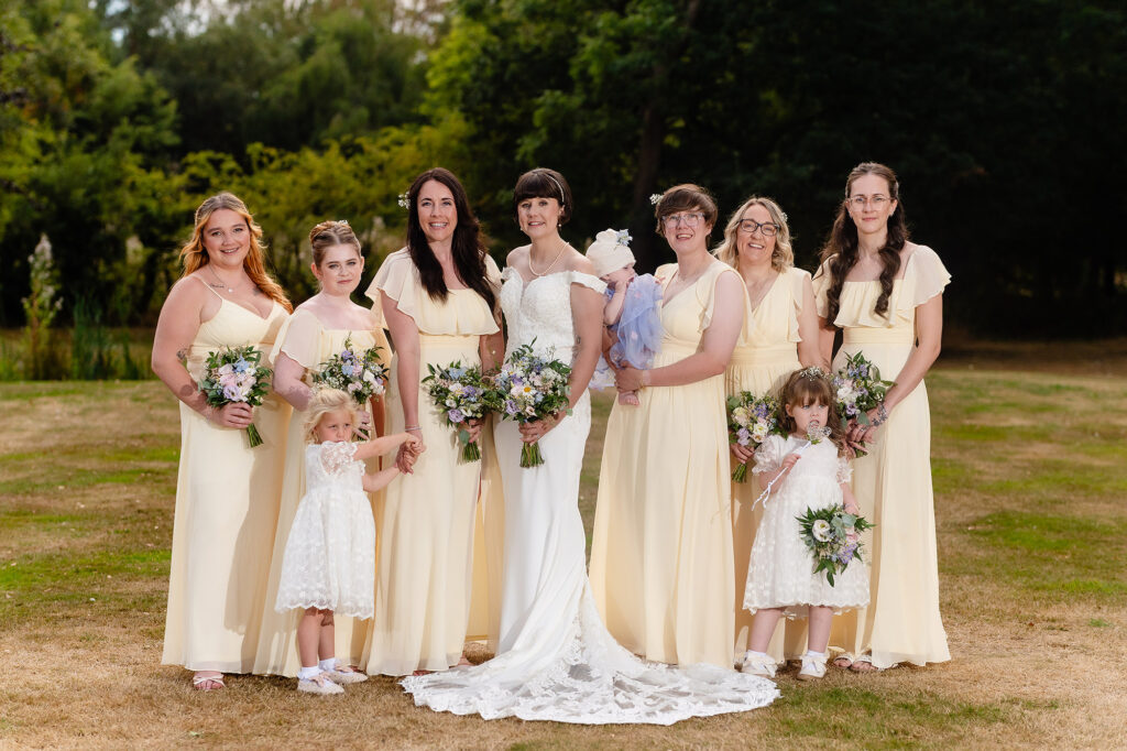 Bride with her bridesmaids in pale yellow dresses and her flower girls, Cheshire wedding photographer
