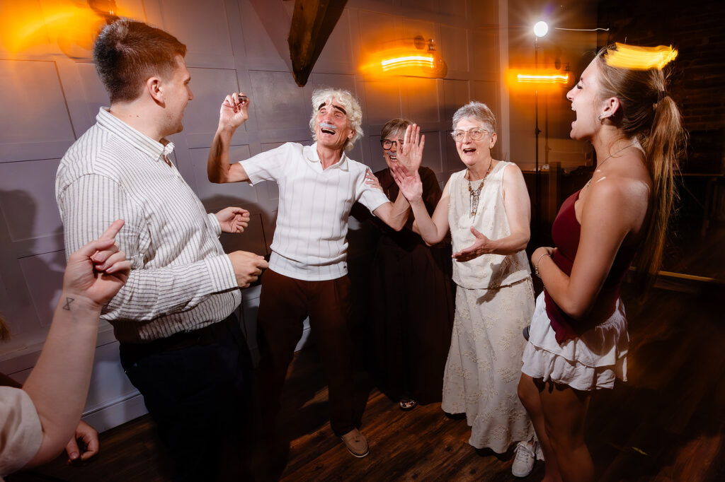 Guests dancing, one wearing a stick on moustache