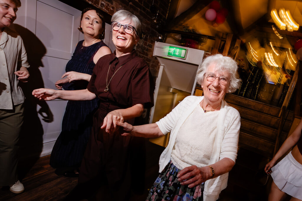 Marianne's Grandma Gina in a white cardigan dancing hand in hand with a guest