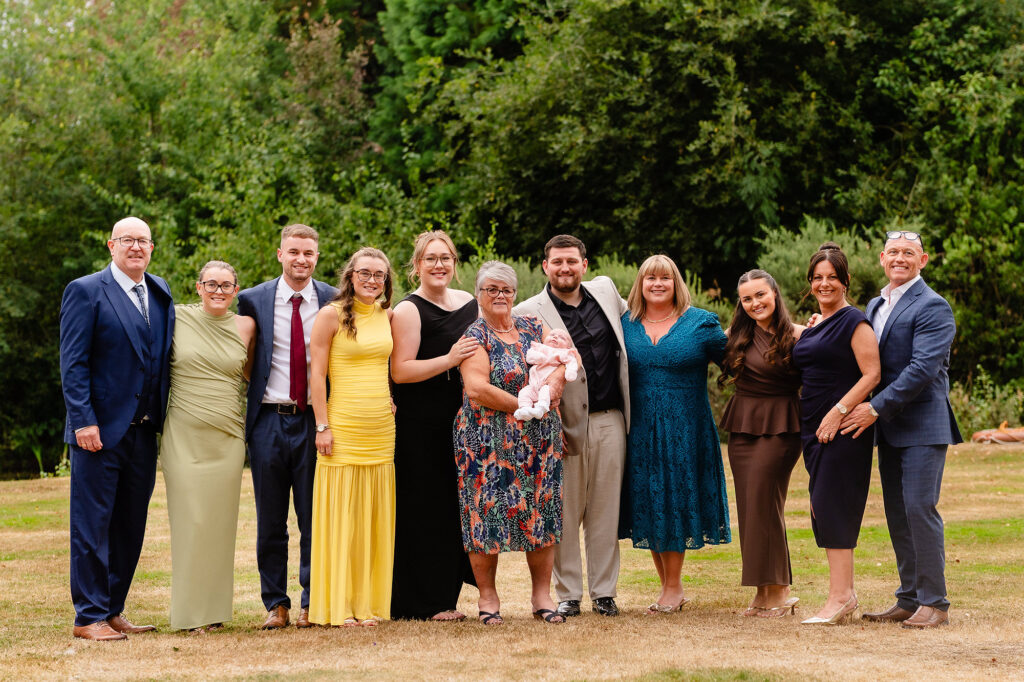 Group of wedding guests lined up on the lawn in the early evening