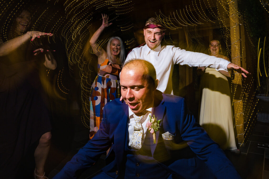 Groom and guests dancing with swirling fairy light trails on the dance floor